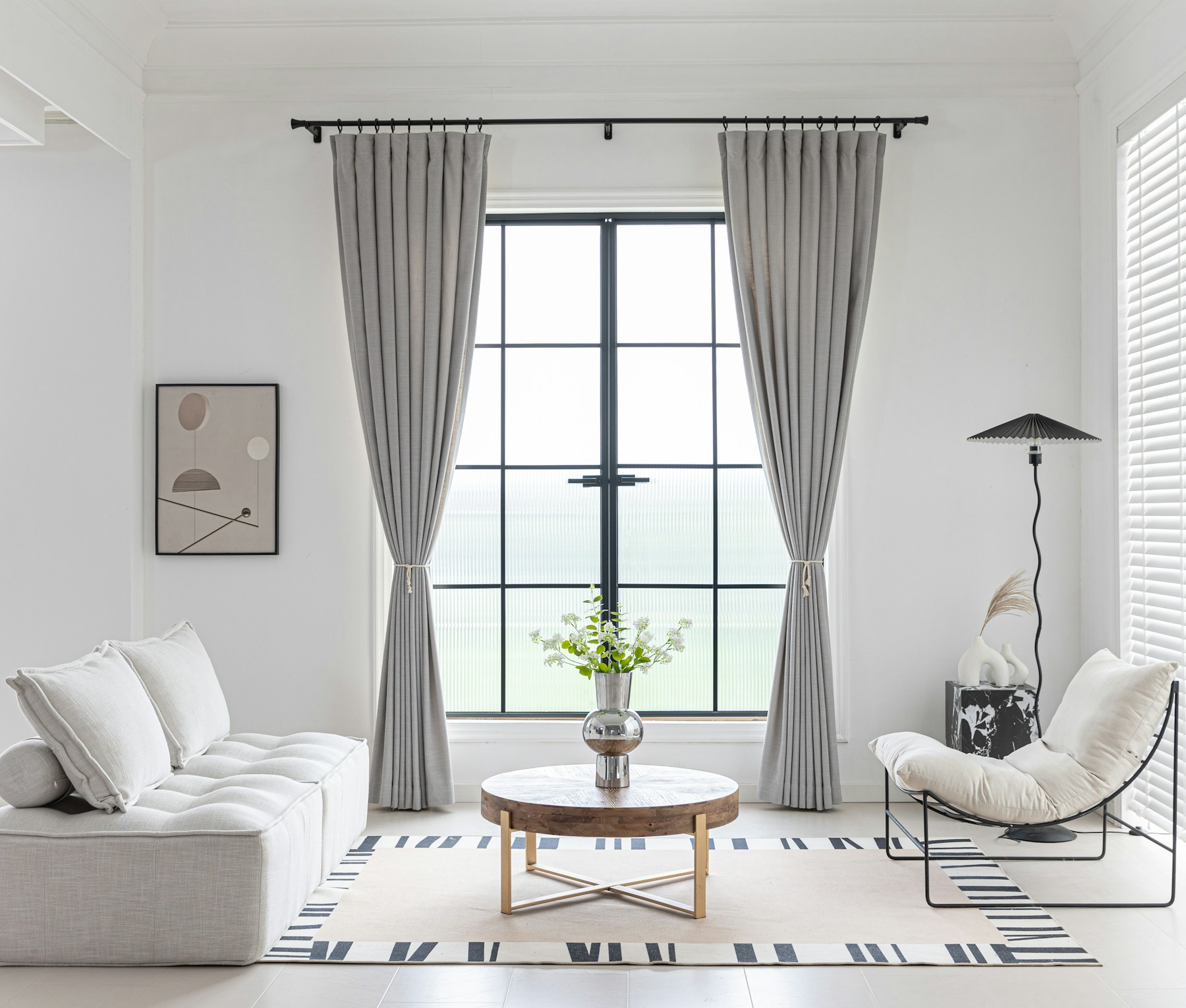 Light-filled Los Angeles living room with neutral furnishings and black-framed window