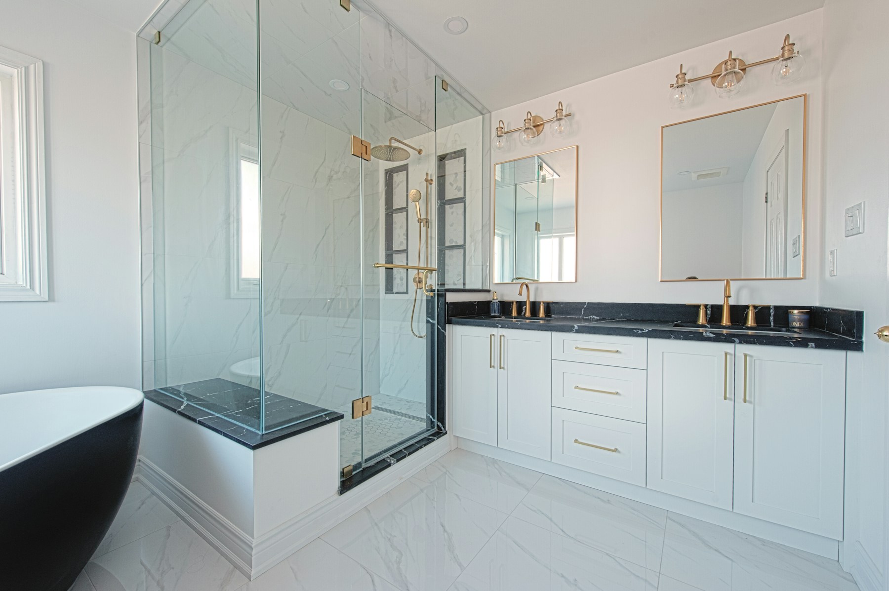 Bright spa-style bathroom with freestanding tub, glass shower, and brass fixtures